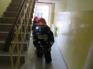 widok strażaków wchodzących do budynku w szyku uzbrojonych w maski tlenowe