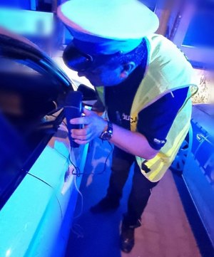 policjant pokazuje kierowcy wynika badania przepuszczalności szyb