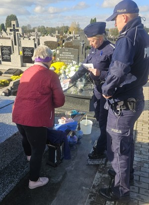 policjanci rozdają ulotki na cmentarzu