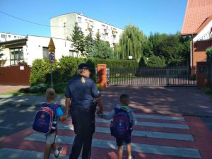 dzielnicowa przeprowadza dzieci przez przejście dla pieszych