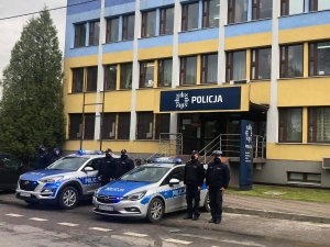 Funkcjonariusze z KPP w Kozienicach przed budynkiem KPP w Kozienicach przy radiowozach oznakowanych oddają hołd zmarłemu na służbie koledze