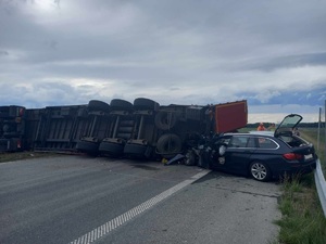 Fotografia kolorowa: droga krajowa S7 zderzenie pojazdu ciężarowego z osobowym. Ciężarówka przewrócona na drogę.
