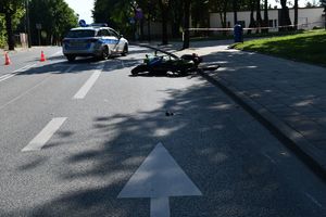 Fotografia kolorowa: Mława, ul. Warszawska,  widzimy leżący motocykl a w oddali radiowóz policyjny.