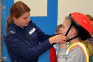 policjantka zakłada dziecku kask ochronny