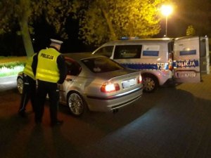 Policjanci stoją przy kontrolowanym samochodzie