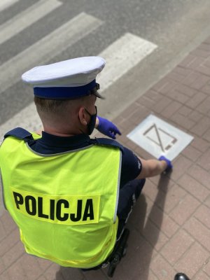 Policjant trzymający szablon na chodniku