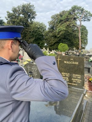 Policjant oddaje honor przed grobem posterunkowego Piotra Walczaka i jego syna posterunkowego Hipolita Walczaka