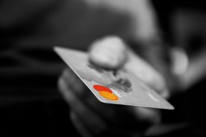 Czarno-białe zdjęcie na którym widać męską dłoń w której znajduje się karta kredytowa