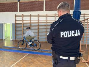 Policjant patrzący na jadącego na rowerze ucznia