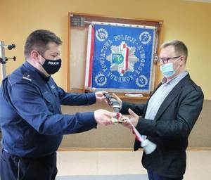 Komendant Powiatowy Policji w Żurominie przekazuje prezent odchodzącemu na emeryturę policjantowi