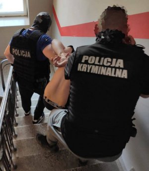 dwóch policjantów z zatrzymanym na schodach
