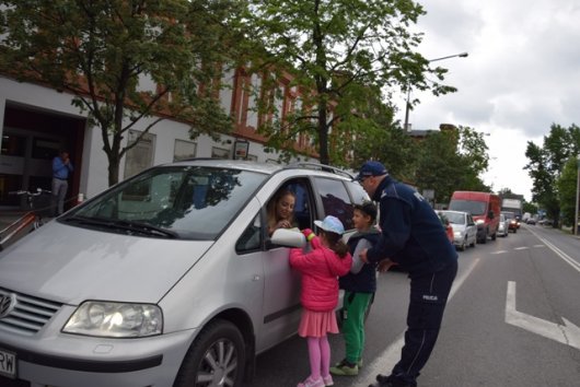 Komendant Powiatowy Policji w Żyrardowie razem z dziećmi przekazuje informacje kierowcy.