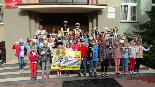Uczniowie uczestniczący w akcji Kierowco! Nie poluj na zebrach wraz z policjantami ruchu drogowego.