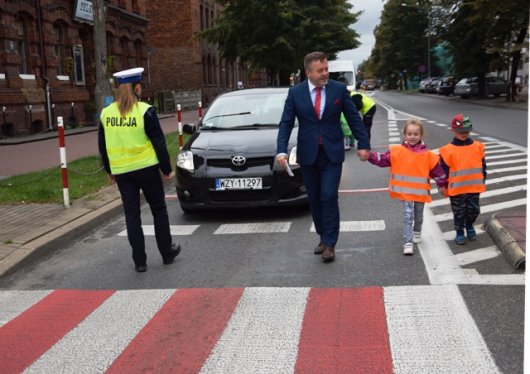 Na zdjęciu Lucjan Krzysztof Chrzanowski Prezydent Żyrardowa z dzieckiem biorącym udział w działaniach. Po lewej stronie policjanta kierująca ruchem