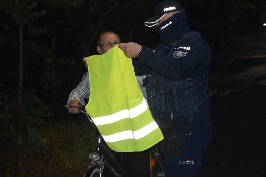 policjant przekazuje kamizelkę odblaskową