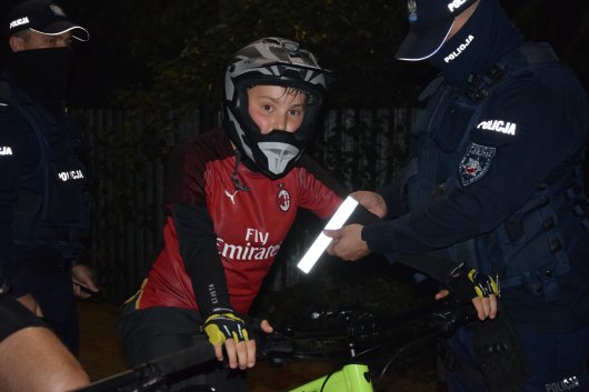policjant zakłada młodemu rowerzyście opaskę odblaskową